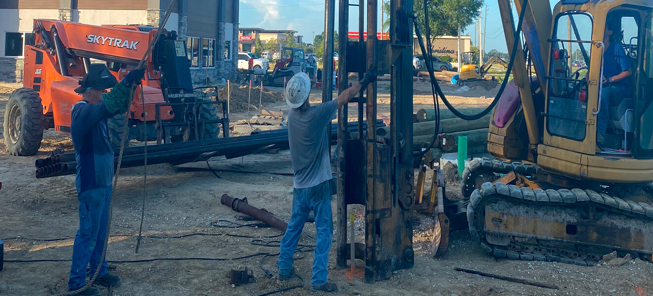 Land pile driving. Construction workers preparing site for pile driving.